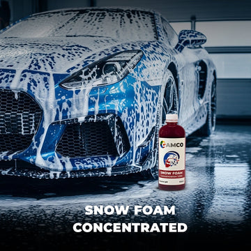 GAMCO Store Snow Foam Concentrated car wash soap bottle next to a blue sports car covered in thick foam.
