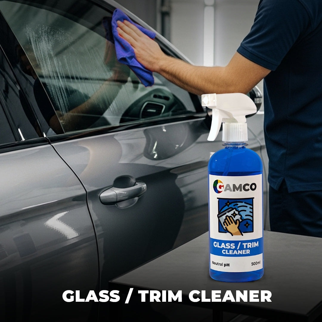 GAMCO Store glass and trim cleaner, a blue spray bottle on a table next to a car being cleaned with a blue microfiber cloth.