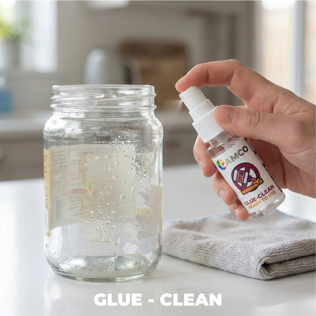 GAMCO Store Glue-Clean spray bottle being used on a glass jar with sticker residue. Microfiber cloth nearby.
