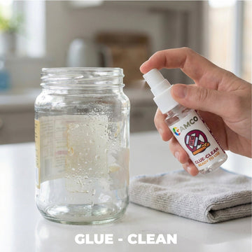 GAMCO Store Glue-Clean spray bottle being used on a glass jar with sticker residue. Microfiber cloth nearby.